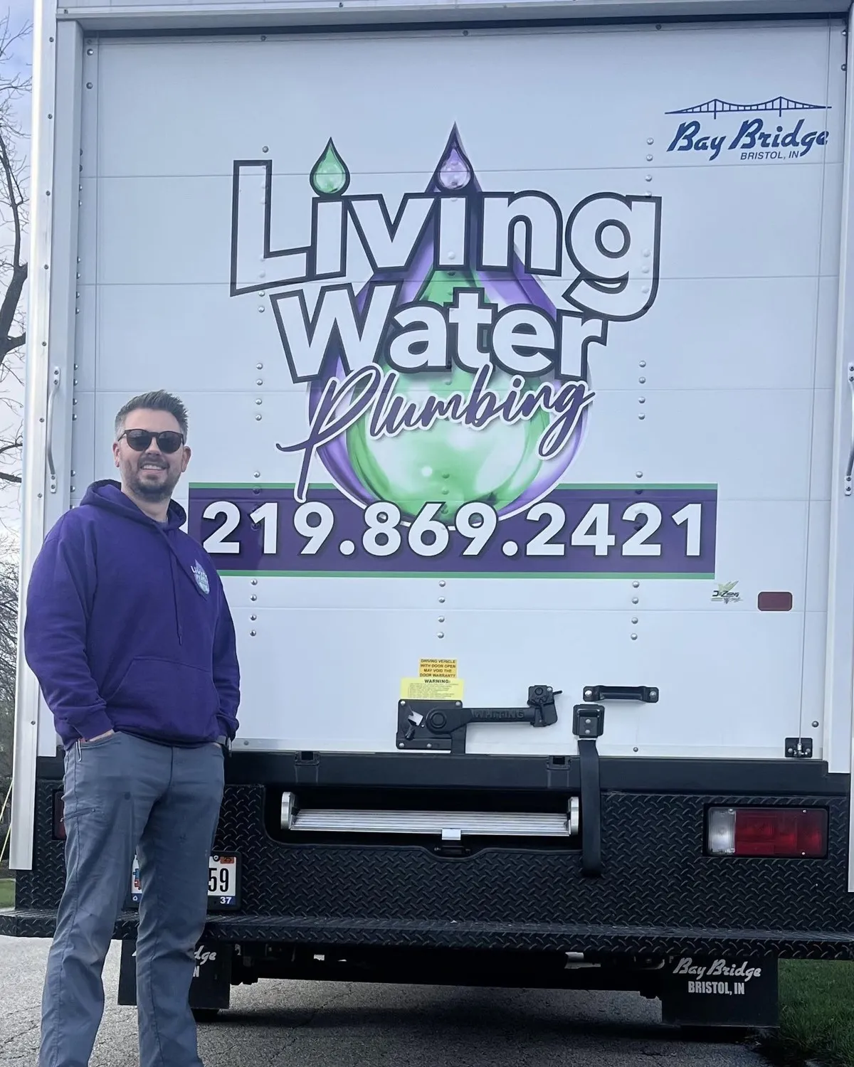 The Living Water Plumbing service truck, lettered with the company's purple and green water-drop logo and the phone number 219.869.2421